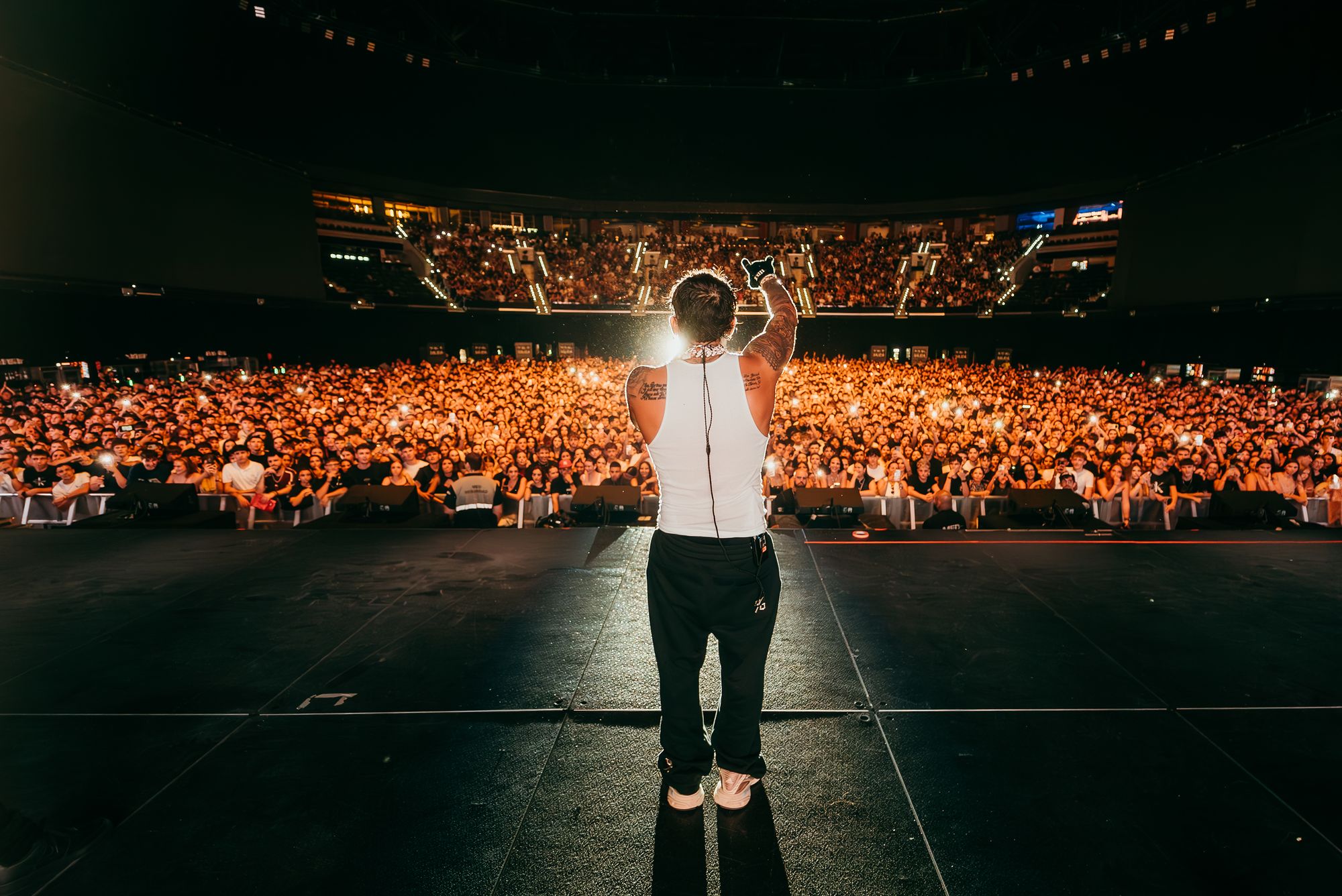 Bryant Myers seen from behind on stage in front of a full Roig Arena in Valencia