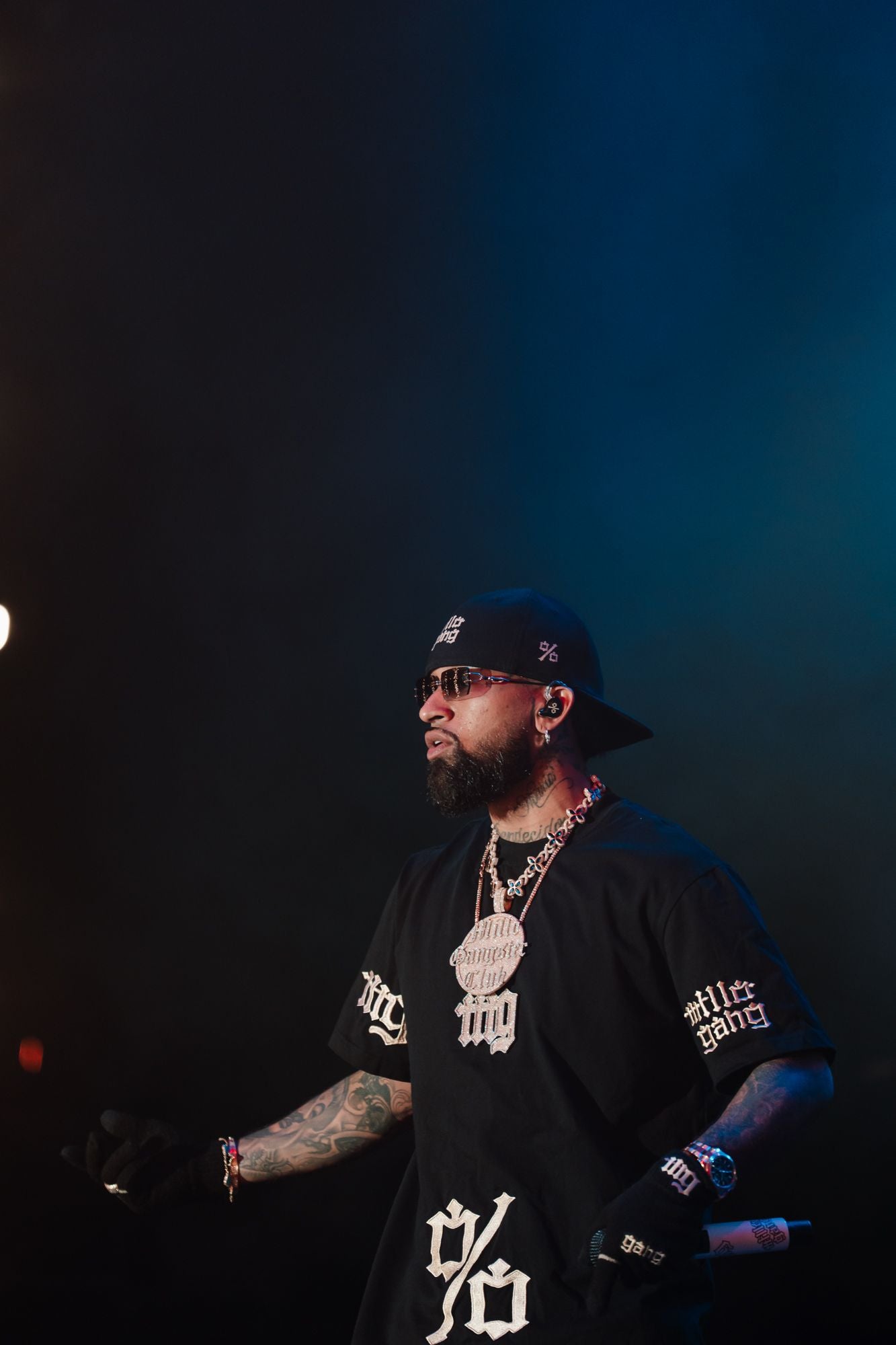 Bryant Myers on stage at Sant Jordi Club wearing the Black Tee with the %, «millo gang» on the sleeves and the % cap